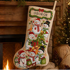 Snowman family cross stitch Christmas stocking with the example name George hanging beside a fireplace