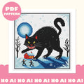 Framed Yule Cat cross stitch design: a giant black cat with yellow eyes above a red snowy cottage, bare trees and two tiny figures under a blue full moon. Pink PDF pattern badge.