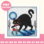 Framed Yule Cat cross stitch design: a giant black cat with yellow eyes above a red snowy cottage, bare trees and two tiny figures under a blue full moon. Pink PDF pattern badge.